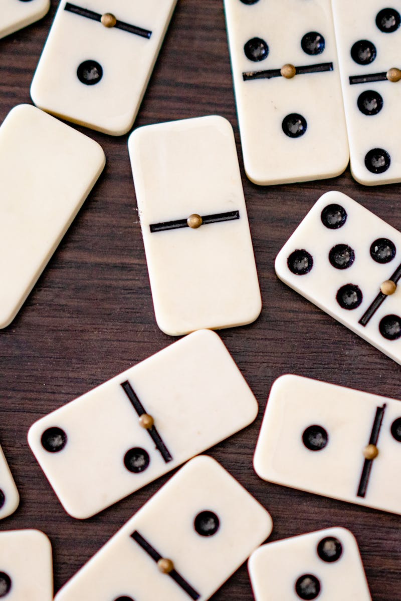 Scattered black and white dominoes on a wooden table, ready for play or leisure.